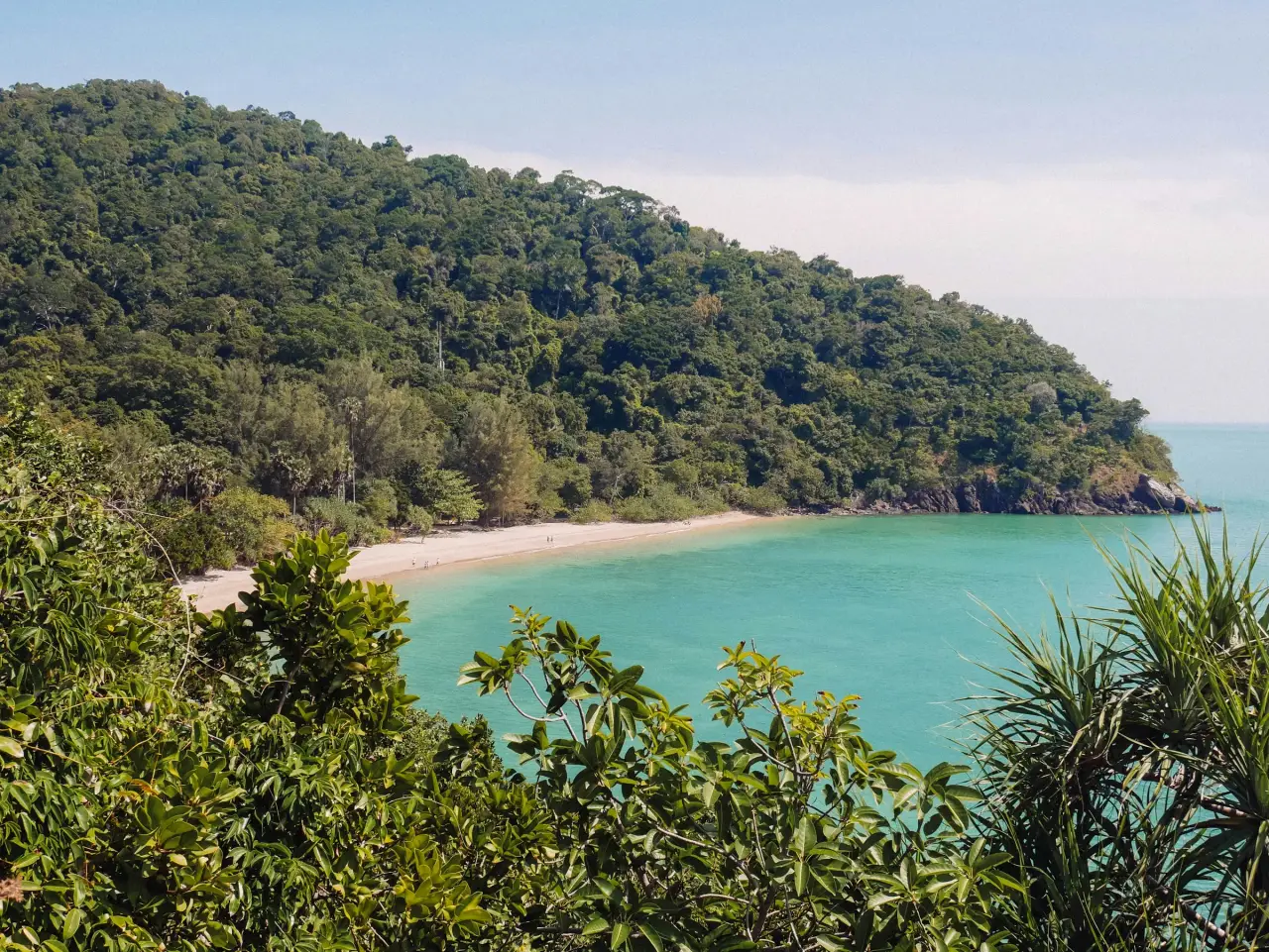 Turquoise water and a white beach below a forested headland in Mu Ko Lanta National Park