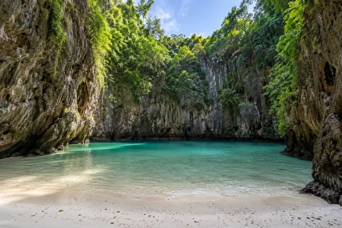 The hidden beach inside Koh Mook’s Emerald Cave, enclosed by forested limestone walls