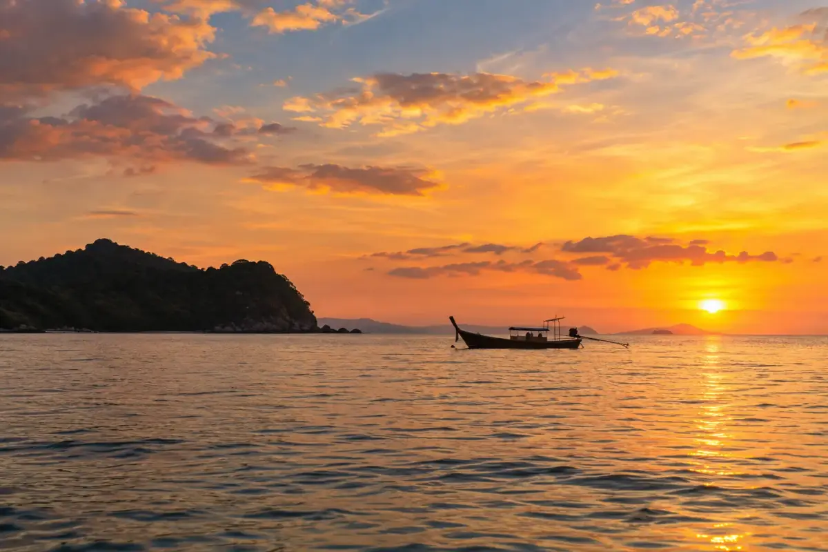 เรือหางยาวไม้ทอดสมออยู่ในแสงอบอุ่นยามเย็น